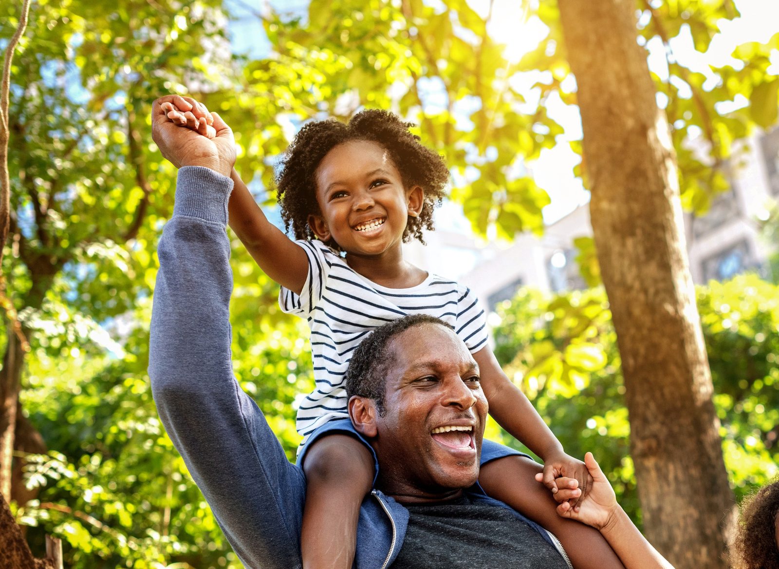 Dad and girl on his shoulders in the park.